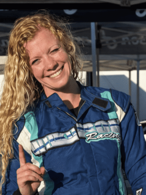 Haylie Wilkinson posing in front of her race car holding up a number 1
